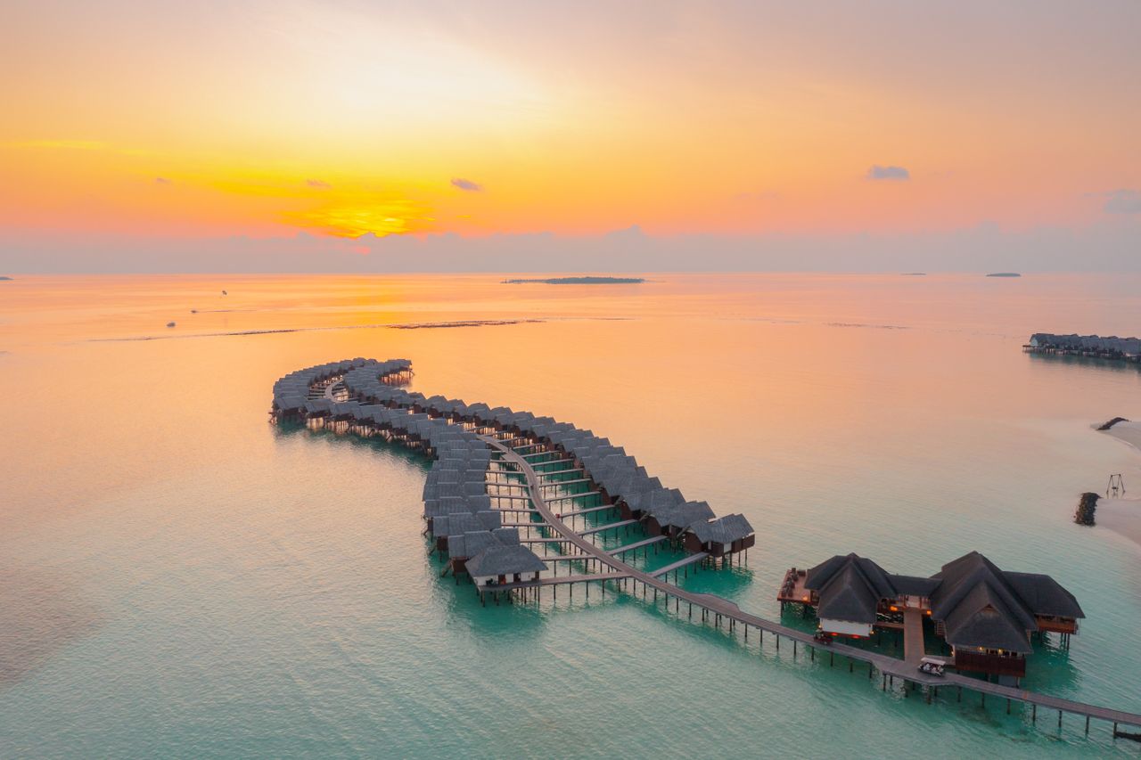 Home A stunning aerial view of overwater bungalows during sunset in Maldives, highlighting serene ocean views.