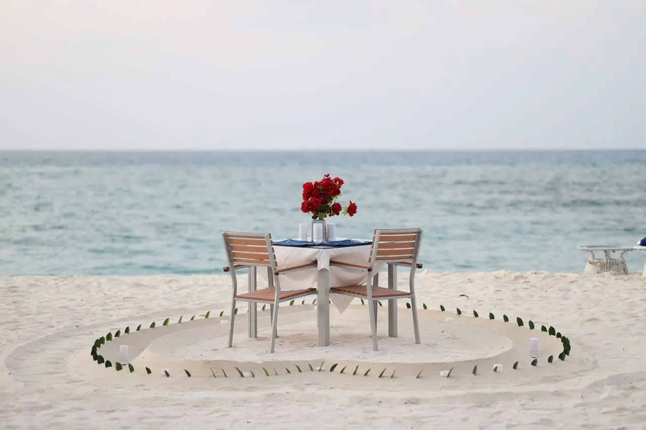 Home Romantic dinner setup on a serene Maldivian beach with ocean view, perfect for couples.