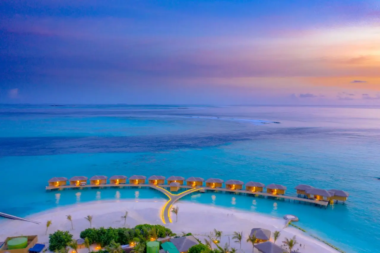 Home A breathtaking aerial shot of overwater bungalows in the Maldives during sunset.