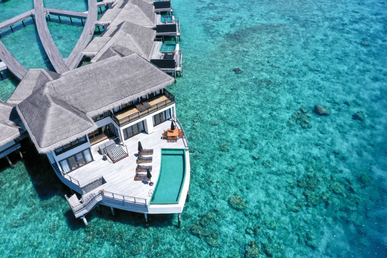 Home Stunning aerial view of luxury overwater villas in a tropical resort with turquoise waters.