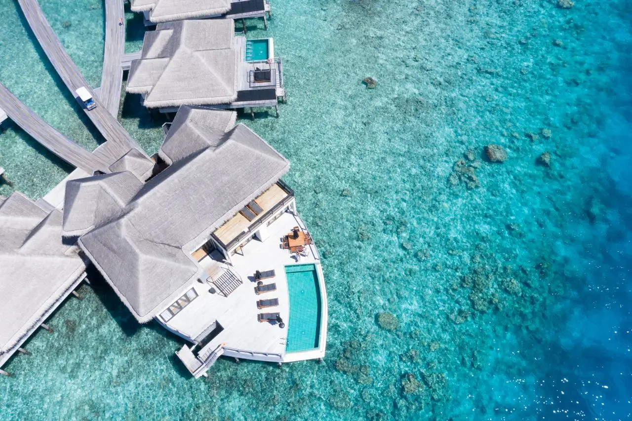 Home Discover a breathtaking aerial view of a luxury resort over vibrant blue waters in the Maldives, perfect for relaxation and escape.